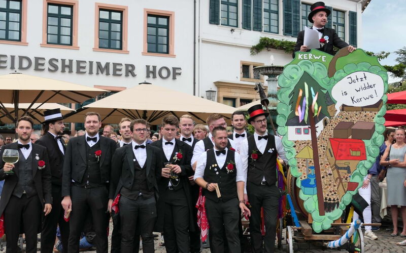 Vor einem historischem Gebäude stehen junge Männer in Frack und Zylinder. die Deidesheimer Kerwebuwe