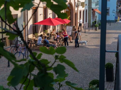 Menschen sitzen vor einem Weinbistro und genießen ein Glas Wein