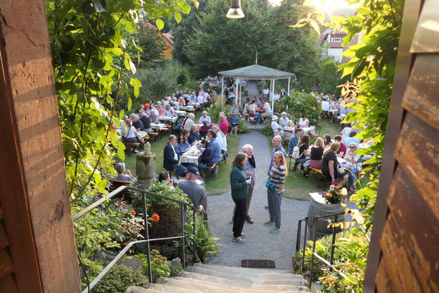 Blick auf die festliche Deidesheimer Weinkerwe mit Gästen, die im Garten an Tischen sitzen und feiern.