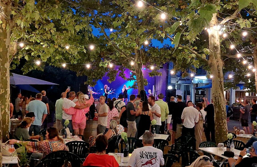 Belebte Atmosphäre bei der Deidesheimer Weinkerwe mit Musik und fröhlichen Gästen unter Lichtern.