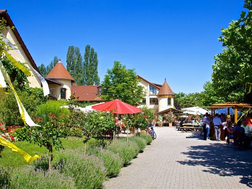 Ein sonniger Tag im Forst Lucashof mit Gästen, die in einem einladenden Garten entspannen und essen.