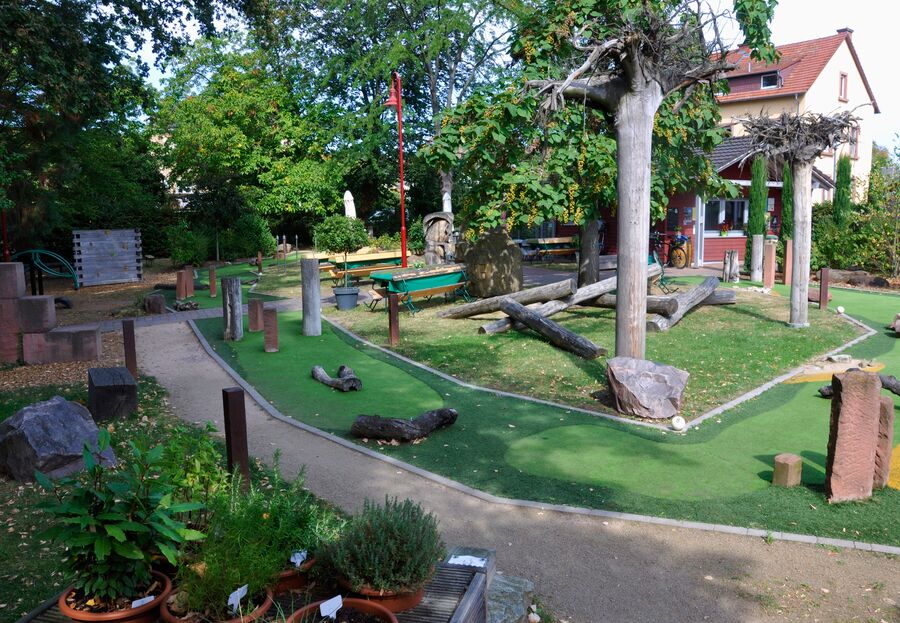 Der Erlebnisgarten zeigt eine grüne Mini-Golf-Anlage mit Holzstämmen und verschiedenen Pflanzen. | © Name