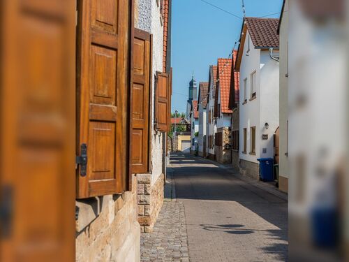 Eine ruhige Straße in Meckenheim mit Holztüren und klassischen Häusern unter klarem Himmel. | © Name