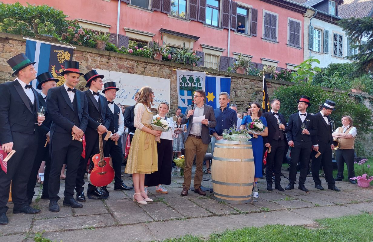 Feierliche Ansprache während der Deidesheimer Weinkerwe mit festlich gekleideten Teilnehmern und einer musikalischen Darbietung.