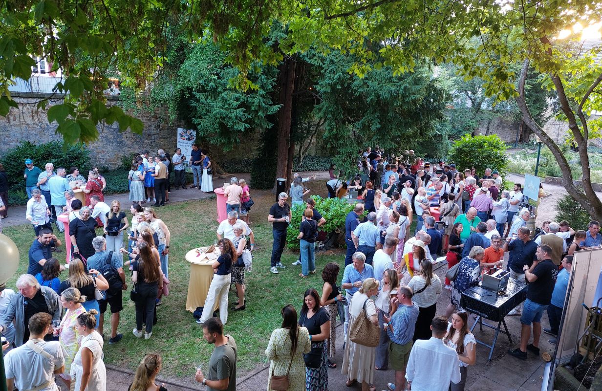 Die Deidesheimer Weinkerwe zeigt eine lebendige Menschenmenge, die in einem schönen Garten feiert und Wein genießt.