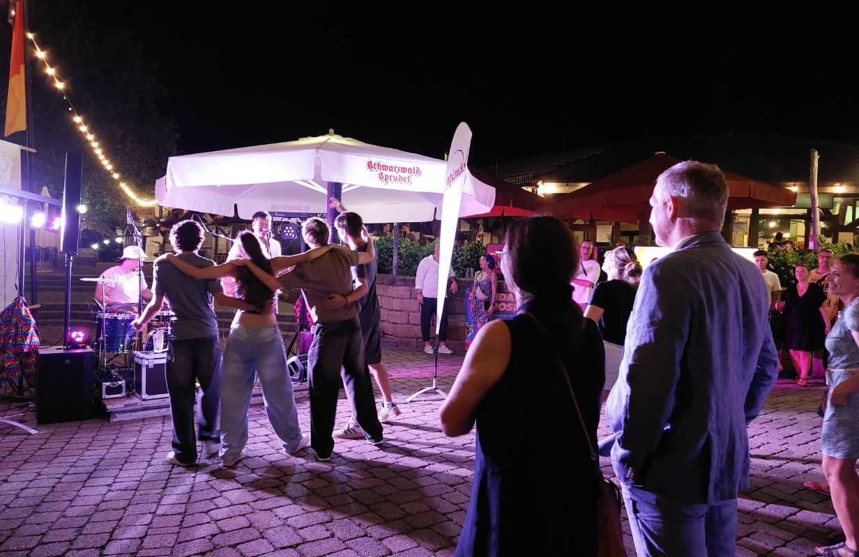 Besucher genießen die Deidesheimer Weinkerwe bei Live-Musik und fröhlichem Tanz unter Lichtern in der Nacht.