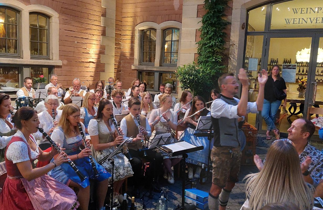 Die Deidesheimer Weinkerwe zeigt eine fröhliche Musikkapelle in traditioneller Tracht bei einem Auftritt im Freien.