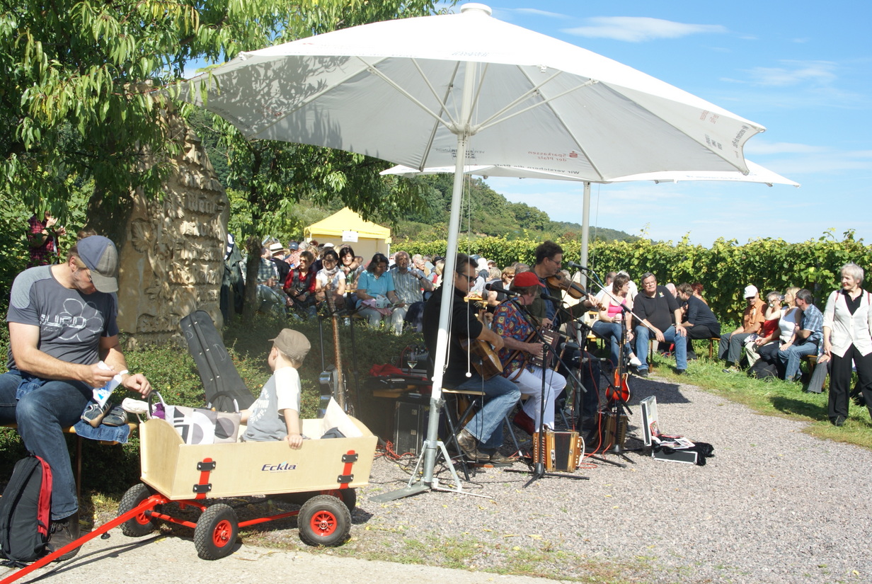 Live-Jazzmusik unter einem Sonnenschirm zieht viele Besucher zu einer Veranstaltung in den Weinbergen. | © Name