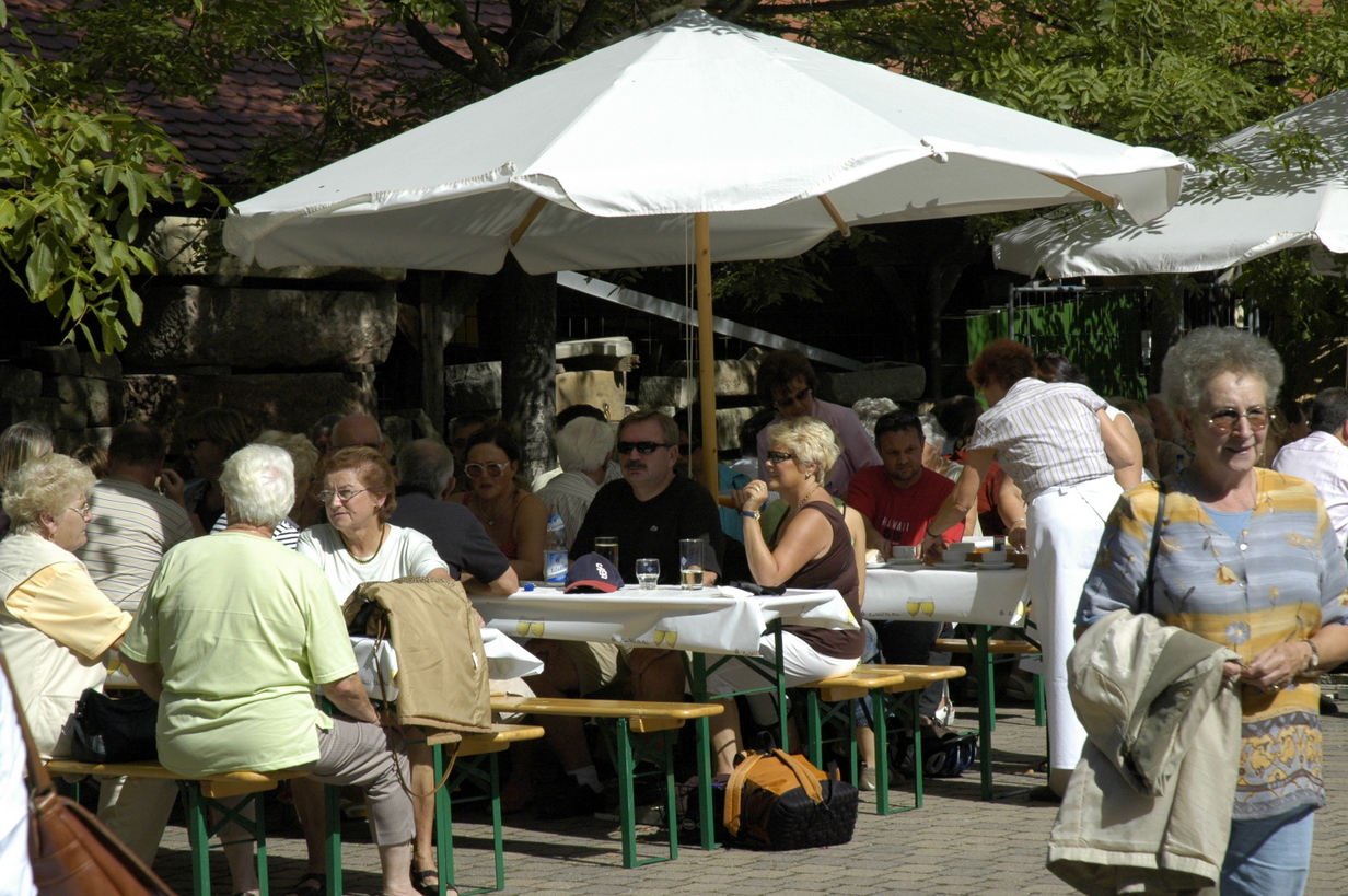 Besucher genießen die Ruppertsberger Kerwe bei Getränken und Gesprächen unter Sonnenschirmen im Freien.